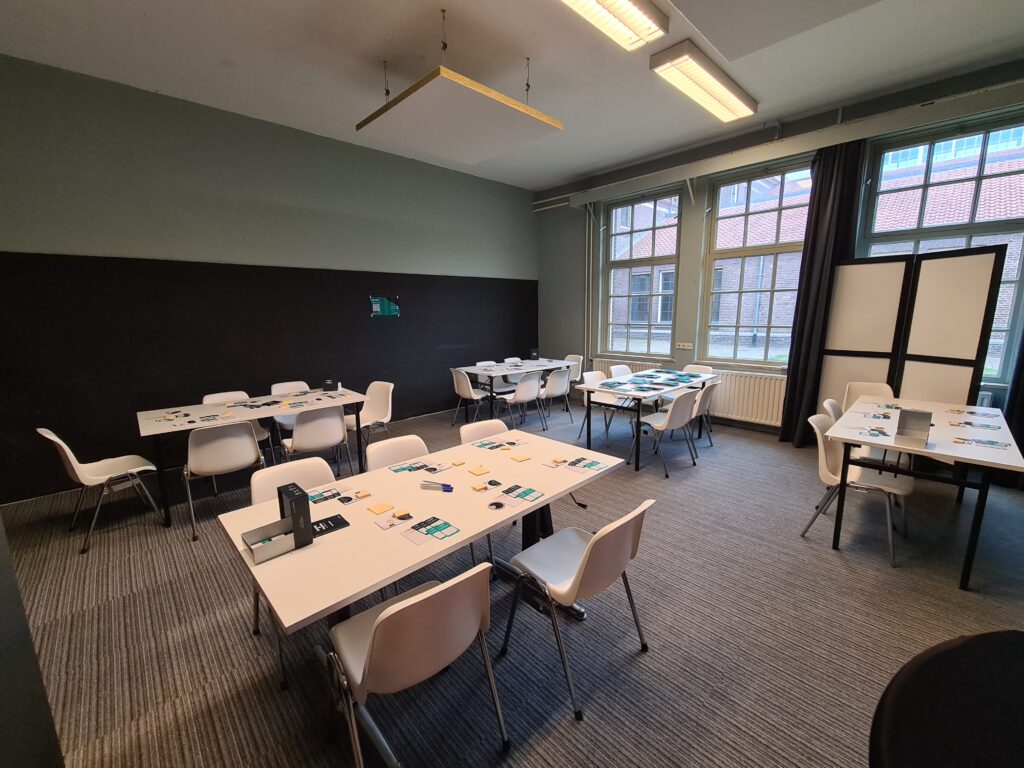 A photo of a room with multiple tables laid out to play Journey of Progress. 