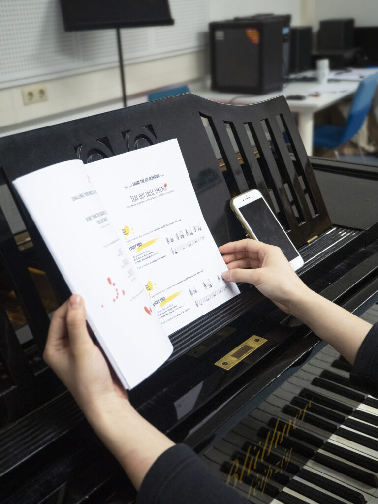 A photo of someone flipping through a booklet at a piano.