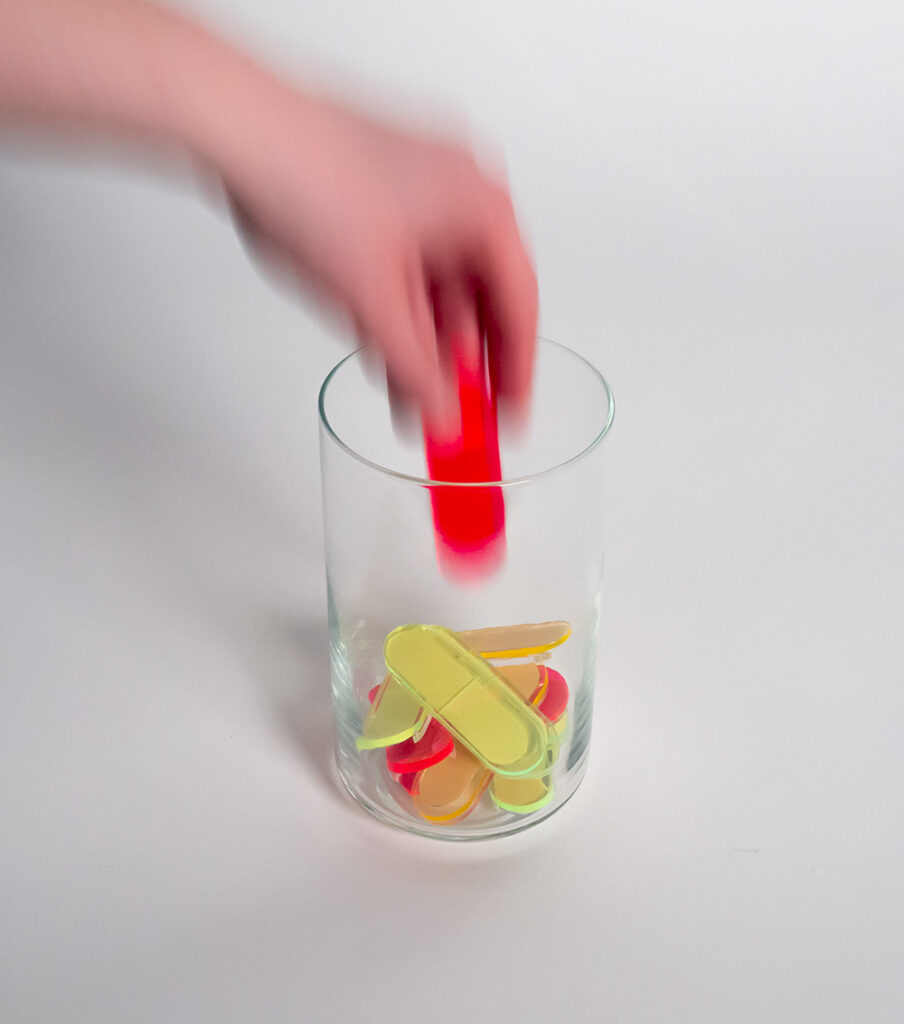 A photo of a glass jar filled with colourful plastic items, with a hand reaching in to take one out.