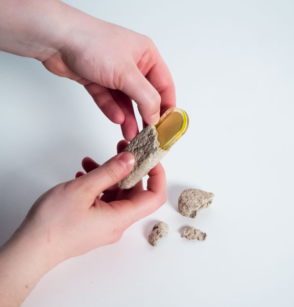 A photo of a pair of hands breaking open the mycelium packaging.