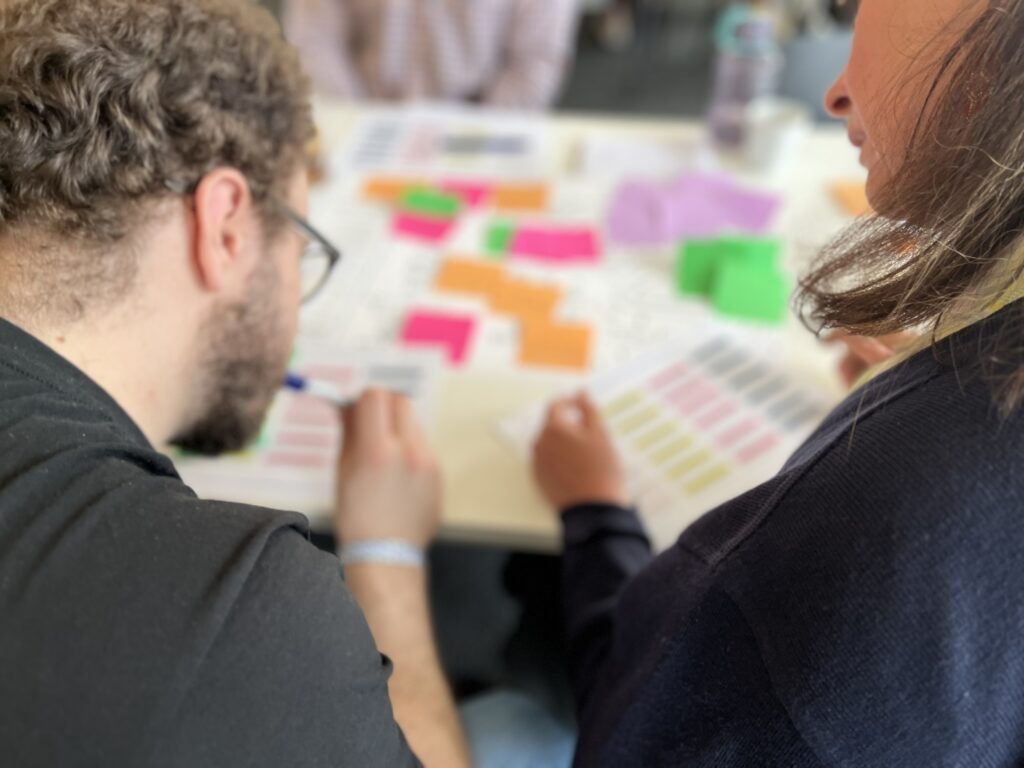 Photo of two people working together over a desk with papers and templates. 