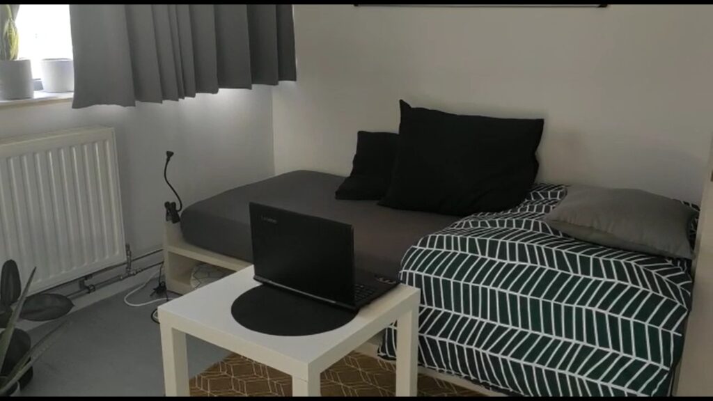 A photo of a room containing a bed and a coffee table with a laptop on it.